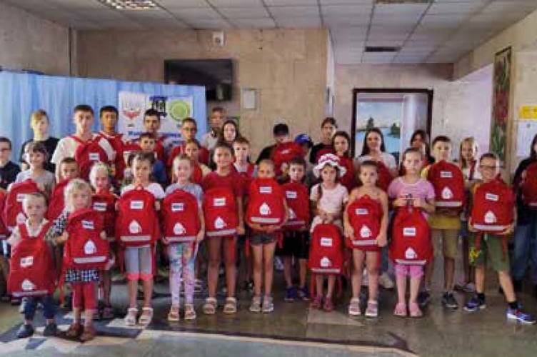 Young Ukrainian pupils show off their School In A Bag rucksacks, September 2023.