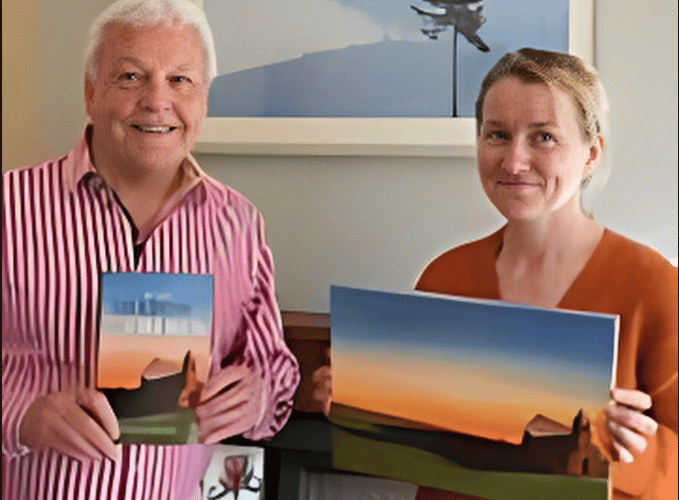 Colin Short and Kirsty Rouse with the book cover design. Behind them is a picture from Kirsty's travels in Rwanda.