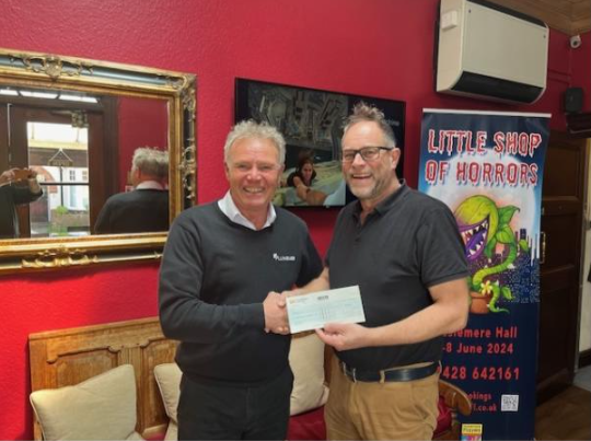 Plumbase manager Philip Morris presents a cheque to Haslemere Hall manager Howard Bicknell, Haslemere Hall, May 2024.